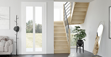 Image d'un intérieur moderne et lumineux avec un escalier en bois sur mesure menant à l'étage.